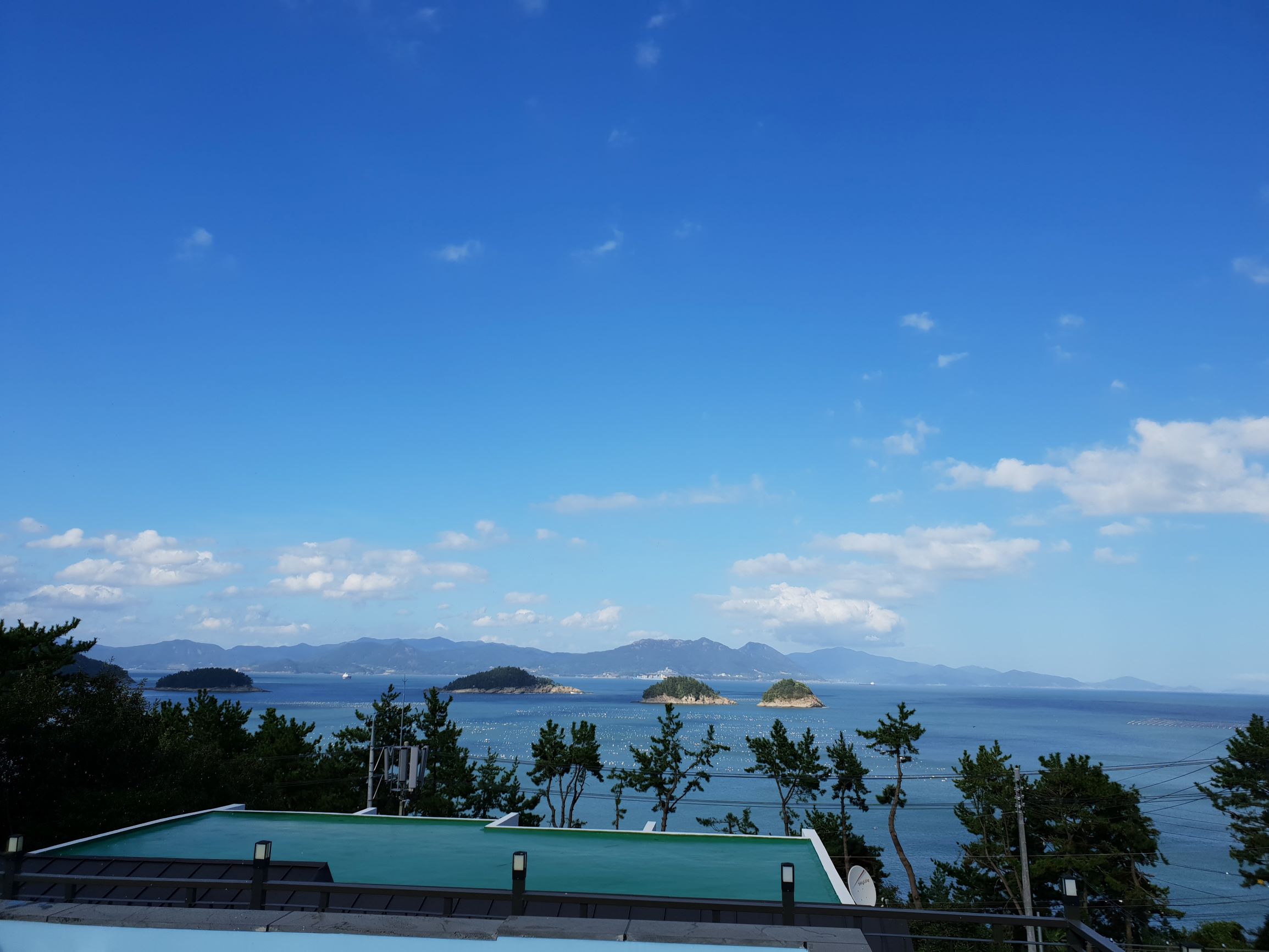 여수의 한 펜션 '아일랜드 보인다'라는 펜션에서 보이는 섬들과 파란 하늘, 그리고 수영장의 모습이다.