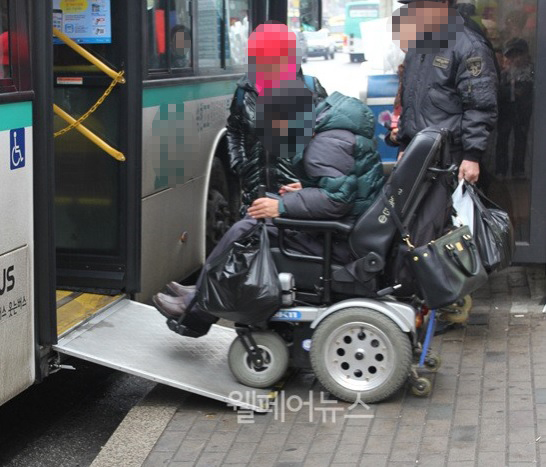 휠체어를 타고 저상버스에 탑승중인 장애인 당사자. ⓒ웰페어뉴스DB