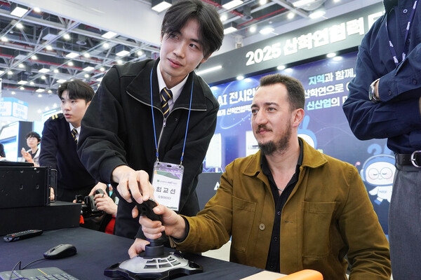 산학연협력 EXPO에서 신라대 학생이 외국인 참여자에게 시뮬레이터 체험을 알려주고 있다.(사진:신라대제공)